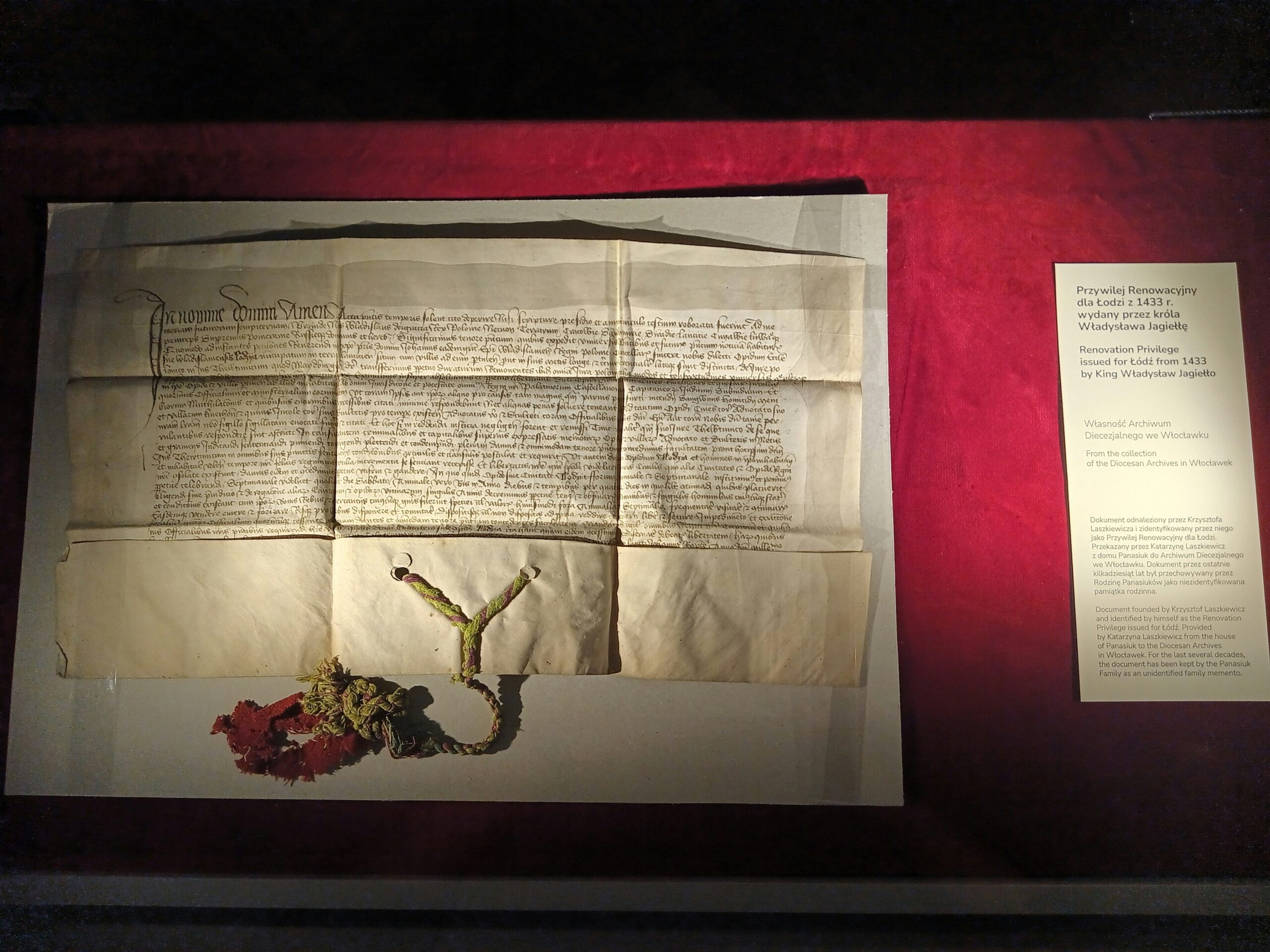 Historic parchment manuscript with handwritten Latin text and seal on a red display background, illustrating the Ancient Library of Alexandria
